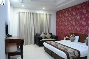 a bedroom with a bed and a chair and a couch at Hotel Asha in Kannauj