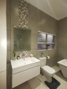 a bathroom with a white sink and a toilet at Utopia Guest House in Alberton +85 photos