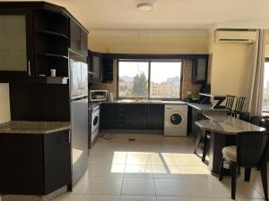 a kitchen with black cabinets and a table and a window at شقق الخامسه الفاخرة Al Amer Luxury Apartments in Aqaba