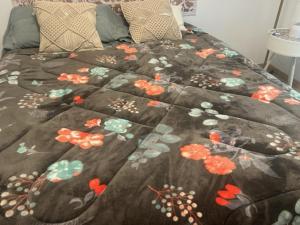 a bed with a blanket with flowers on it at APARTAMENTO PALOMAREs in Zújar