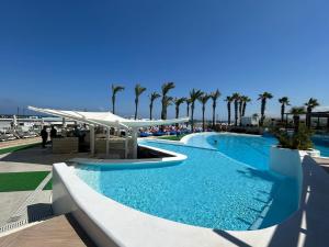 a large swimming pool with palm trees in the background at Riviera Hotel and Beach Lounge, Beirut in Beirut