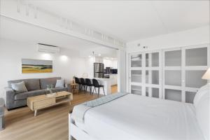 a white bedroom with a bed and a living room at Ilikai Tower 1936 condo in Honolulu