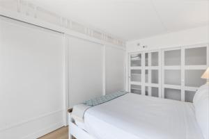 a white bedroom with a bed and white cabinets at Ilikai Tower 1936 condo in Honolulu