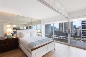 a bedroom with a white bed and a balcony at Ilikai Tower 1936 condo in Honolulu