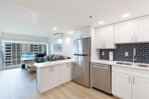 a kitchen with a refrigerator and a living room at Ilikai Tower 1936 condo in Honolulu +17 photos