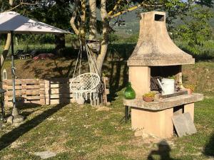 a outdoor oven with a chair and an umbrella at Cuore di Legno Country House in Spoleto