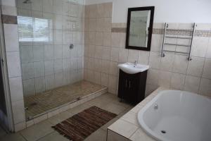 a bathroom with a shower and a tub and a sink at Shores Keep - Self Catering Home in Hermanus