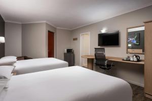 a hotel room with two beds and a desk at Protea Hotel by Marriott Cape Town Tyger Valley in Bellville