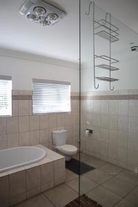 a bathroom with a tub and a toilet and a shower at Shores Keep - Self Catering Home in Hermanus