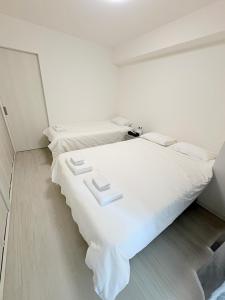 a white bedroom with two beds and a mirror at カリエンテ三宮202 in Kobe +1 photo