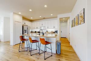 a kitchen with white cabinets and orange chairs at a counter at Tranquil Desert Sanctuary in Indio