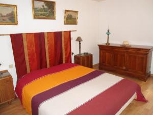 a bedroom with a colorful bed with a wooden dresser at villa Périgord in Monteton