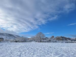a snow covered field with houses in the background at Casa María in Baltar