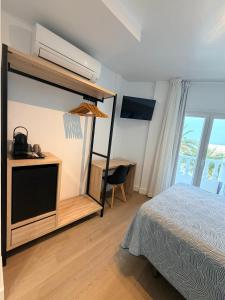 a bedroom with a bed and a desk with a television at Hostal Juan Carlos in Carboneras