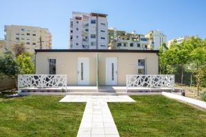 a building with white doors and a grass yard at Villa Hoxha 80 in Durrës