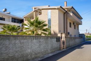 a house with a retaining wall and palm trees at Villa Hoxha 80 in Durrës