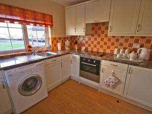 a kitchen with a washing machine and a sink at Cloverfield in Bamburgh