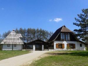 une maison avec un toit mansardé sur un terrain herbeux dans l'établissement Cottage Vodice, à Zlatibor