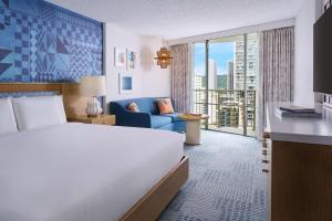 a hotel room with a bed and a couch at OUTRIGGER Waikiki Paradise Hotel in Honolulu