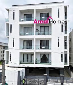 a white building with a red real homes sign on it at M&N Apartment in Ikate
