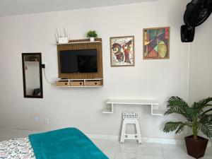 a bedroom with a tv on a white wall at Tropical Loft in Niterói