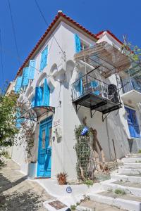 a white building with blue doors and a balcony at Plomari Nest in Plomari