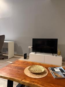 a living room with a table and a tv at KingsWay Mezzanine in Ágios Rókkos