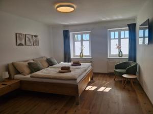 a bedroom with a bed and a chair and windows at Dreimäderlhof Ferienhaus in Karlstetten