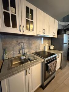 a kitchen with white cabinets and a sink and a stove at KingsWay Mezzanine in Ágios Rókkos