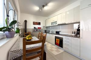 a kitchen with white cabinets and a table with a bowl of fruit at Ferienwohnung Frangipani in Utjeha