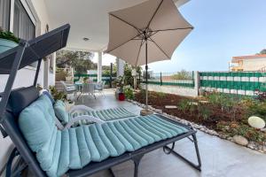 a patio with a couch and an umbrella at Ferienwohnung Frangipani in Utjeha