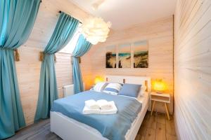 a bedroom with blue curtains and a bed with two towels at Domek -Tiny House Resort Marino in Grzybowo