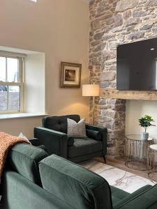a living room with two green couches and a stone wall at Kittys Haven in Castlemaine +7 photos