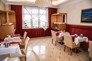 a restaurant with white tables and chairs and a chandelier at Hotel Corvinus Vienna in Vienna