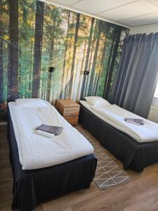 two beds in a room with a forest mural at Hotell Hemgården in Bengtsfors