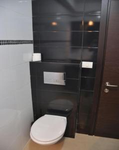 a bathroom with a white toilet and a black wall at Isramax Jerusalem Apartment in Bat-Yam in Bat Yam