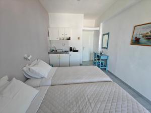 a white bedroom with a large bed and a kitchen at Kamelia in Kokkari