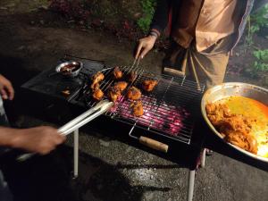 a person is cooking food on a grill at Enchanting woods Yercaud in Yercaud