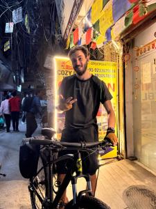 a man standing next to a bike in front of a store at Cozy Inn Hostel in New Delhi