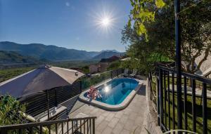a swimming pool with an umbrella and a person sitting in it at Beautiful Home In Vrgorac in Vrgorac +39 photos