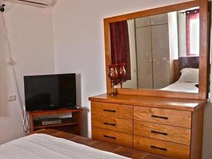 ein Schlafzimmer mit einer Kommode mit einem Spiegel und einem TV in der Unterkunft Lea's - Spirit of the Galilee in Migdal