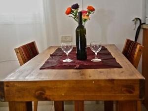 uma mesa de madeira com dois copos e um vaso com flores em Lea's - Spirit of the Galilee em Migdal