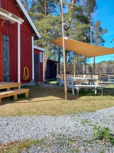 a picnic table with a large umbrella next to a red barn at Hemma fran Hemma - Tipi Glamping in Kvillsfors