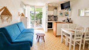 a living room with a blue couch and a kitchen at MES VACANCES A LA MER studio 4 pers, parking privé, wifi, linges fournis, climatisation in La Grande Motte +28 photos