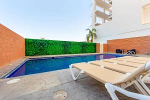 a swimming pool with two lounge chairs next to a brick wall at Sleep Inn Mazatlan in Mazatlán