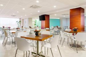 a dining room with tables and white chairs at Sleep Inn Mazatlan in Mazatlán