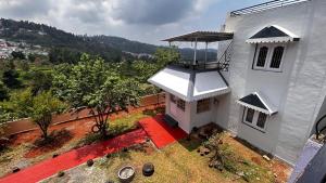 an aerial view of a white house with a red porch at Valley homes in Ooty