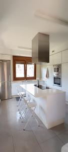 a kitchen with a white counter and chairs in it at Casa Agarimo in Arcade