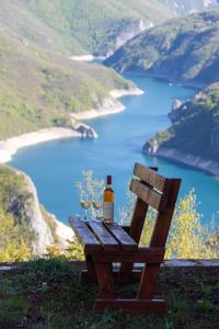 a bottle of wine sitting on a bench overlooking a lake at Rural Resort Tron in Plužine