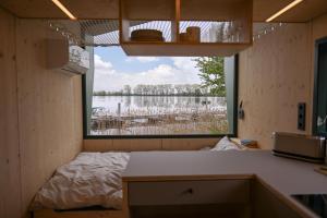 a small room with a bed and a large window at Tiny House Nook 3 - Green&Tiny Hideaway Eider in Süderstapel